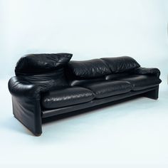 a black leather couch sitting in front of a white wall