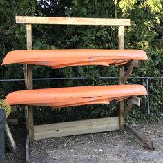 three orange surfboards are sitting on a rack in front of some bushes and trees