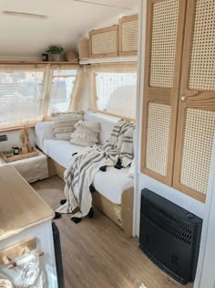 the inside of a camper with wood flooring and white couches, windows, and shelves