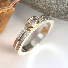 a diamond ring sitting on top of a rock next to an orange leaf and stone