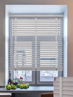 a kitchen window with blinds and fruit on the counter