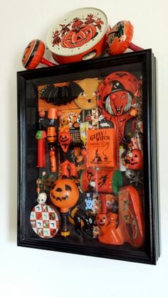 there is a black frame with many halloween items on it and an orange bowl in the middle