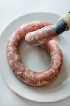 two sausages on a white plate with a paintbrush in the middle one is round