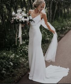 a woman in a white dress is walking down the road with her bouquet on her shoulder