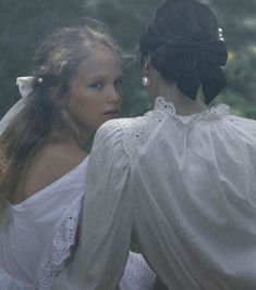 two women dressed in white are facing each other