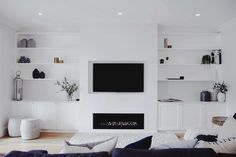 a living room filled with furniture and a flat screen tv mounted on the wall above a fireplace