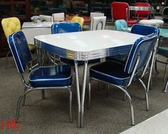 a white table surrounded by blue chairs in a room filled with other tables and chairs