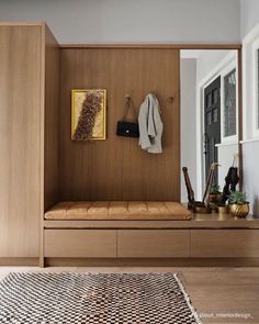 a wooden bench sitting in the middle of a living room next to a wall mounted coat rack