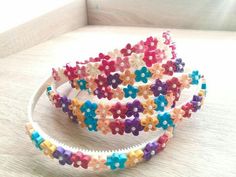 three different colored flower headbands sitting on top of a white table next to each other