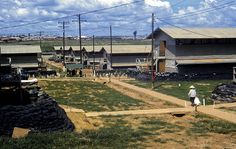 a man walking down a dirt road next to houses