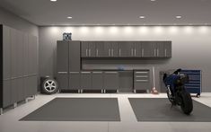 a motorcycle is parked in a garage with grey cabinets and gray floor mats on the floor