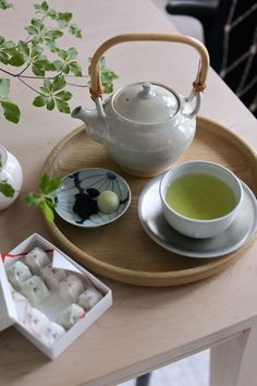 a tea tray with two cups on it next to a potted plant