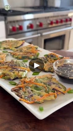 an image of food on a plate in the middle of a kitchen counter with a bowl of dipping sauce