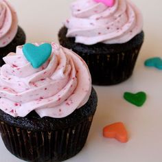 three cupcakes with pink frosting and hearts on top