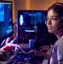 a woman wearing headphones sitting in front of two computer monitors