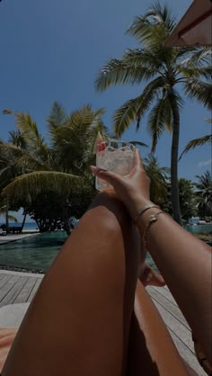 a woman sitting on the beach with her legs crossed and holding a plastic bottle in front of her