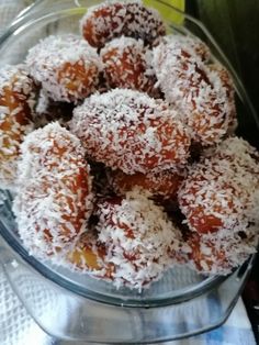 a glass bowl filled with powdered sugar covered donuts on top of a table