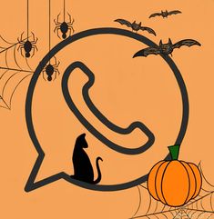 a cat sitting in front of a phone with bats and pumpkins on the background