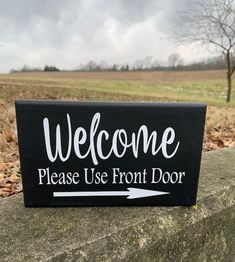 a sign that says welcome please use front door with an arrow pointing to the right