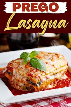 a white plate topped with lasagna covered in sauce and basil garnish