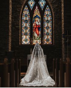 the bride's veil is covering her face in front of an ornate stained glass window