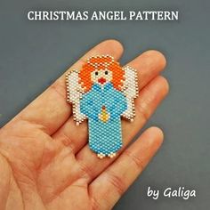 a hand holding a small cross stitch angel