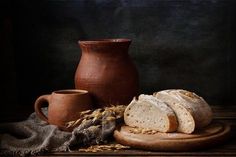 a loaf of bread sitting on top of a wooden cutting board next to a vase