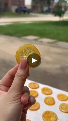 a person is holding an orange slice in front of some cookies on a table outside