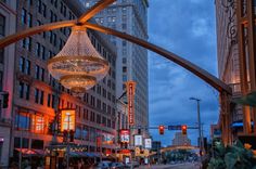 a city street filled with tall buildings and lots of traffic under a chandelier