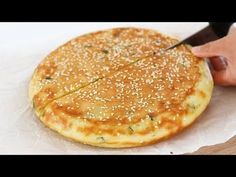 a person cutting into a pizza on top of a piece of paper with a knife