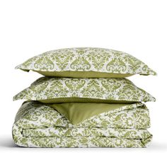 three pillows stacked on top of each other with green and white designs in the middle