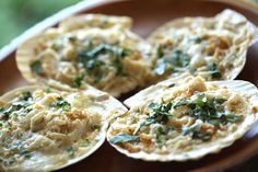 an assortment of baked food items on a wooden plate with green garnishes