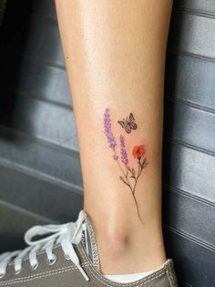 a woman's foot with flowers and a butterfly tattoo on the side of her leg