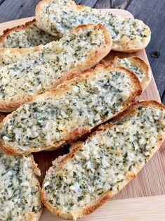 garlic bread on a cutting board with cheese and herbs