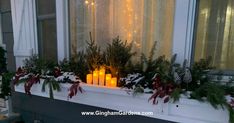 a window sill filled with candles and evergreens