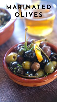 an orange bowl filled with olives on top of a wooden table