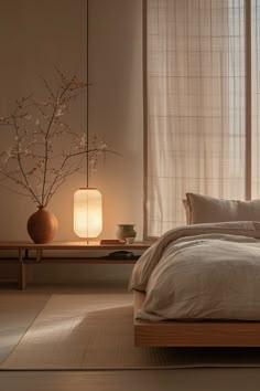 a bed sitting in a bedroom next to a table with a lamp on top of it