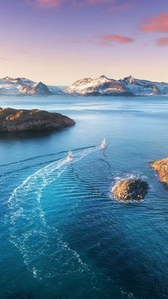 an aerial view of the ocean and mountains with a boat in the water near it