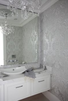 a bathroom with a sink, mirror and chandelier