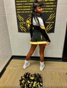 a girl in a cheerleader uniform is standing next to a pile of pom - poms