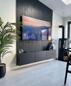 a large television mounted to the side of a wall in a living room next to a plant