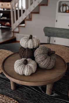 three knitted pumpkins sitting on top of a wooden table in front of stairs