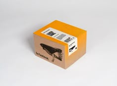 an orange box with a black bird on the front and back side, sitting on a white surface