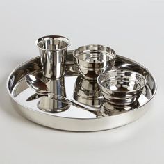 a silver plate with cups and spoons on it, sitting on a white surface