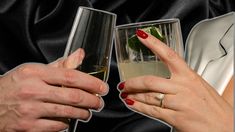 two people holding champagne glasses with their fingers in the air and one has a ring on it's finger