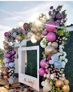 a decorated entrance with balloons and flowers on the outside, in front of a mirror