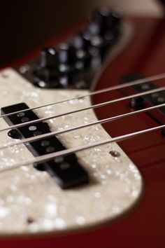 an electric bass guitar with black and white knobs on it's pickuper