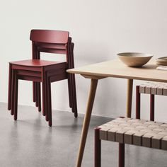 two wooden chairs sitting next to each other in front of a table with a bowl on it