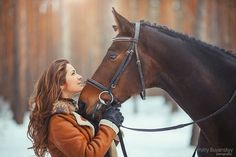 a woman is standing next to a horse in the snow