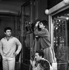 black and white photograph of two people standing in front of a building with camera equipment